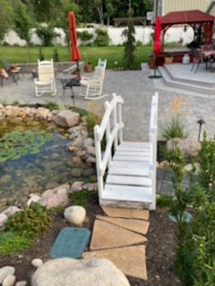 Garden pond with white bridge and patio seating