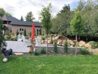 Backyard with pond, garden bridge, flowering plants and mature trees